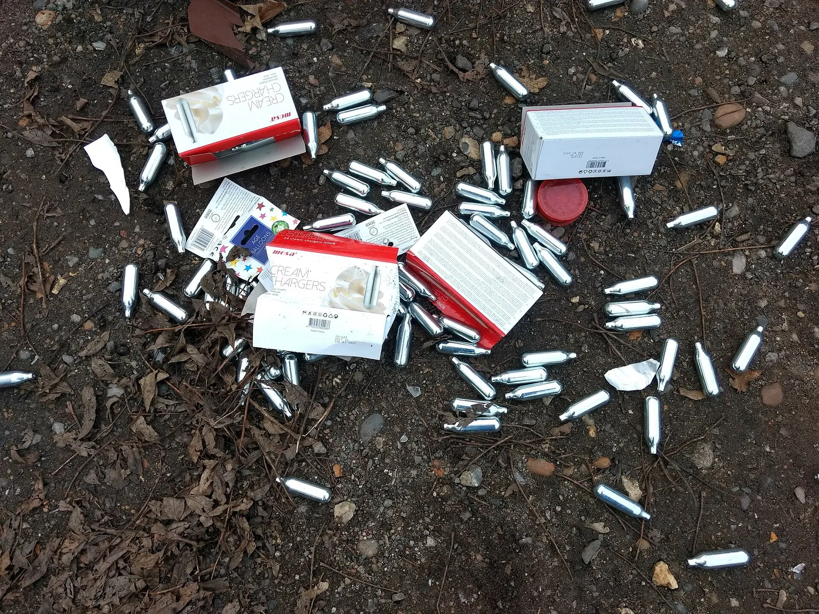 Slängda lustgaspatroner på en parkeringsplats (arkivbild)