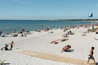 Badande vid en svensk strand en varm sommardag
