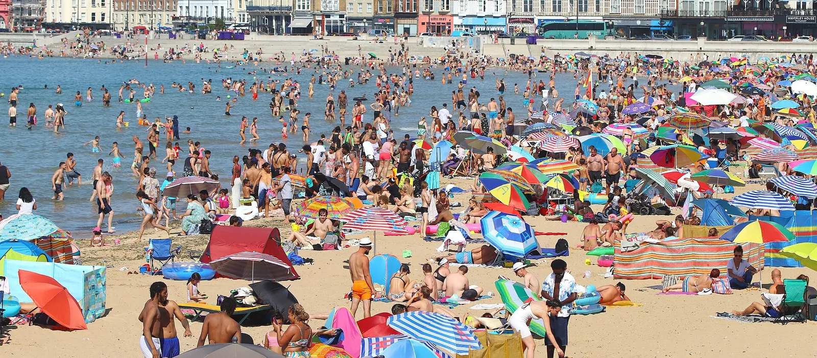 Människor söker svalka på en strand under en värmebölja