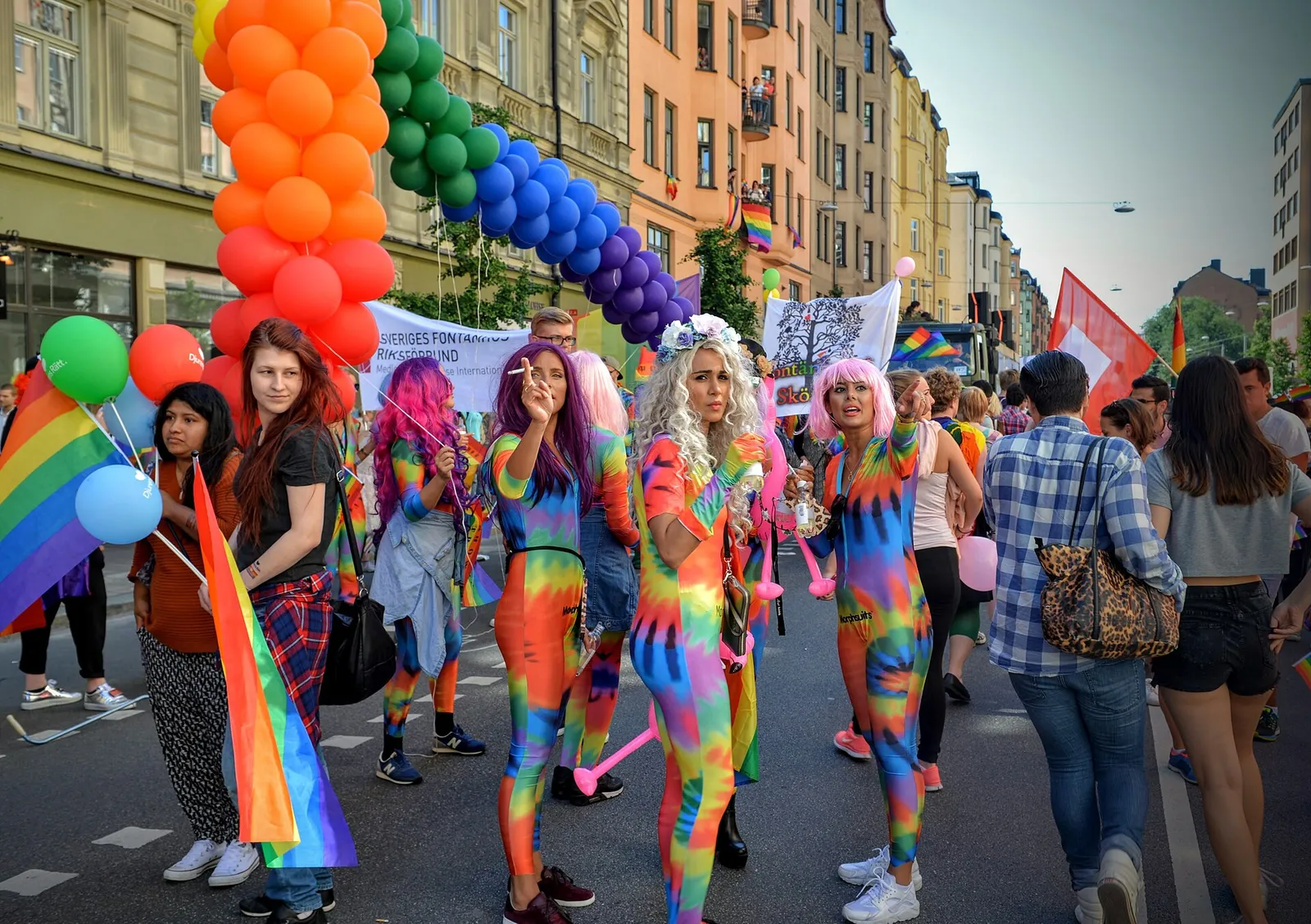 Deltagare med regnbågsflaggor i ett pridetåg