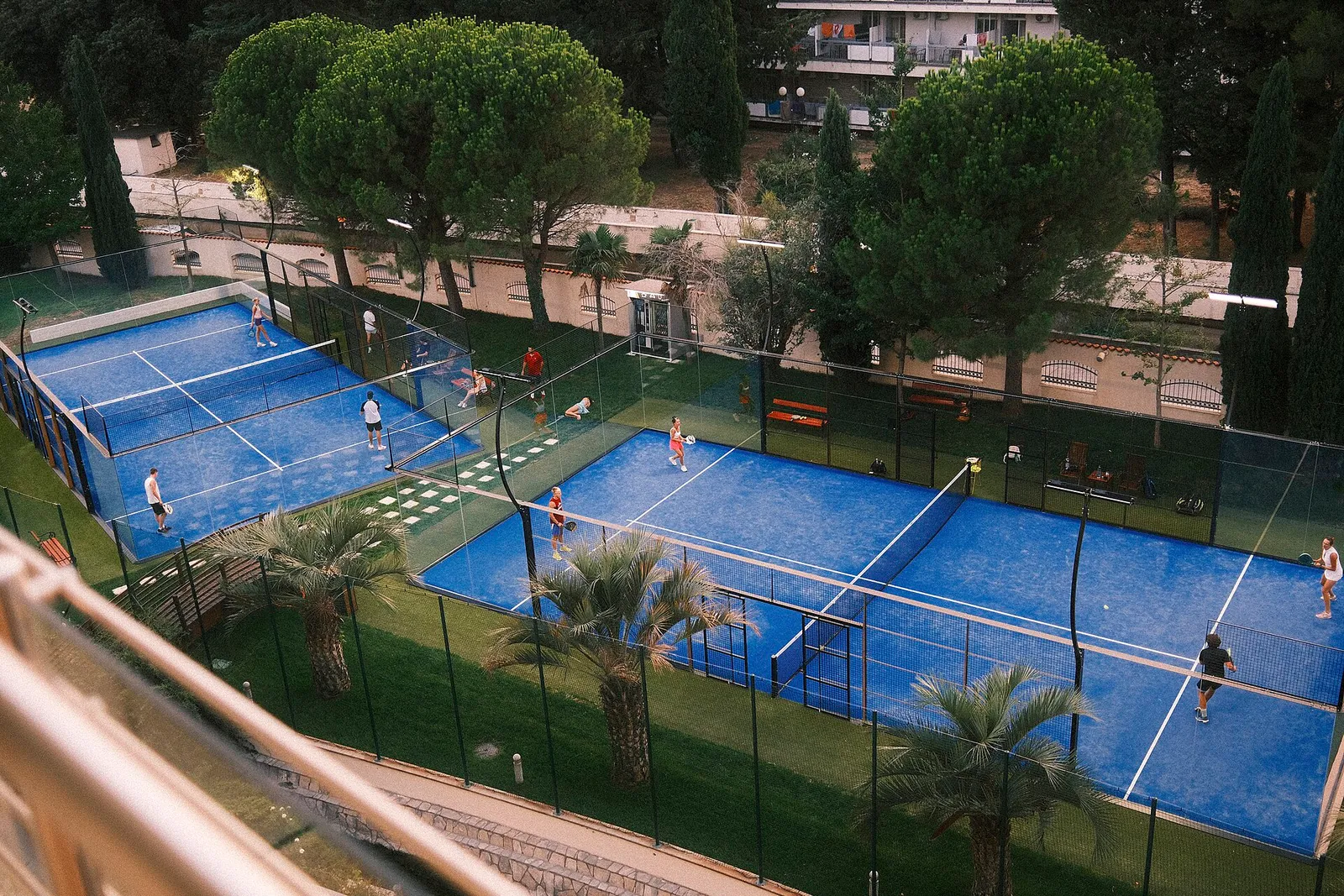 Spelare i en padelmatch på en bana omgiven av grönska