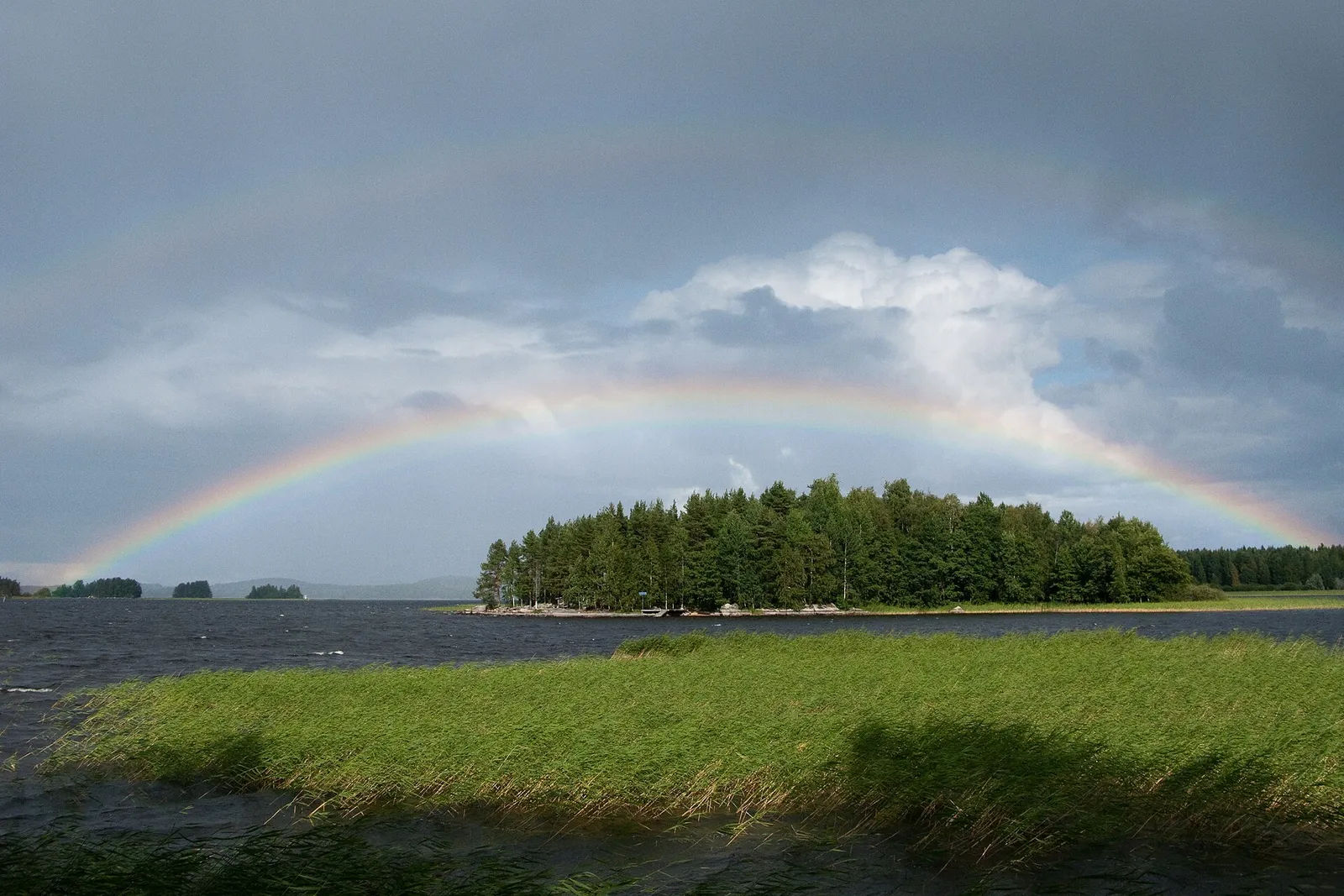 En dubbel regnbåge över en nordisk sjö