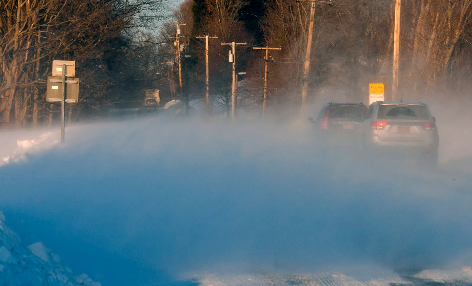 Bilar kör på snöig väg i drivsnö, arkivbild